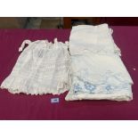 An Edwardian embroidered bedspread; a Victorian child's lace dress and a table cloth
