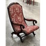 A Victorian mahogany and upholstered parlour chair with scrolled open arms and a turned stretchers