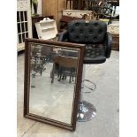 A bar stool and a wall mirror with bevelled plate