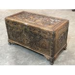 A Malaysian cedarwood chest, carved to the lid, sides and front with scenes in bas-relief. 40' wide