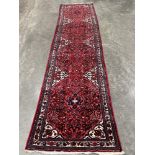 An Iranian red ground carpet runner. 144' x 34'