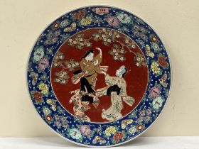 An oriental charger decorated with dancers, prunus, flying insects and foilage. 18' diam.