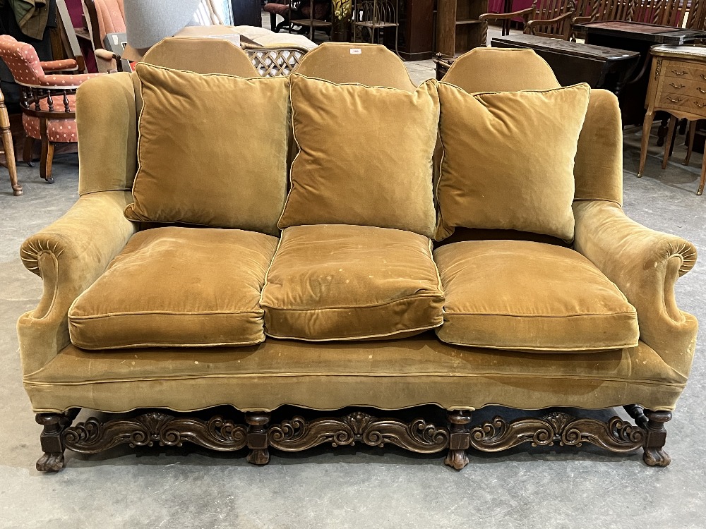 An early 20th century oak and upholstered triple chair back settee on Braganza feet and scroll