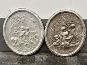 A pair of composition oval plaques, moulded in relief with putti in a garden. 31" high.
