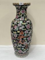 An oriental vase, decorated with dragons and chrysanthemums on a black ground. 25" high. Crack and