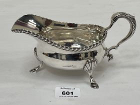 A George V silver sauce boat with scrolled handle on three shell mooulded feet. Sheffield 1923.