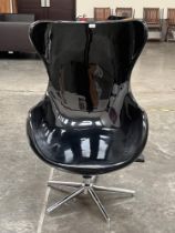 A designer style armchair in black polycarbonate on swivel stand.