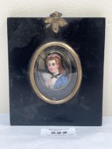 A 19th century portrait miniature of a young lady with a fan. Painted in enamels on a porcelain oval