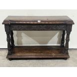 An antique joined oak side table, the inverted break fronted top over a carved frieze, on baluster