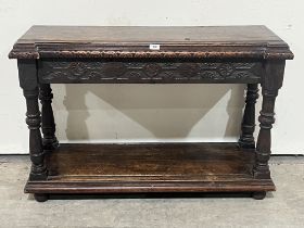 An antique joined oak side table, the inverted break fronted top over a carved frieze, on baluster