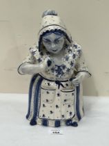 A 19th century Delft figural jar and cover, in the form of a lady taking snuff. 11½" high.