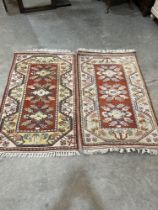A pair of Turkish red ground rugs. 54" x 32". One faded.