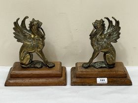 A pair of brass griffins on oak bases. 10" high.