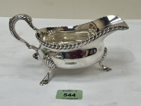 A George V silver sauce boat with scrolled handle on three shell moulded feet. Sheffield 1923. 7¾"