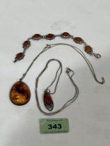 A silver and amber cabochon bracelet and two silver and amber pendants on necklet chains.