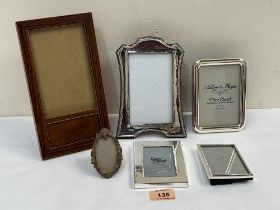 A silver photograph frame, four plated frames and a treen example.