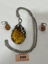 A large silver and amber pendant and chain with a pair of silver and amber earrings.