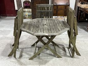 A teak garden table with three folding chairs.