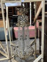 A gilt metal chandelier of ten lights hung with pendant drops. Partially dismantled. 48" high.