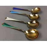 A CASED SET OF FOUR SILVER GILT AND HARLEQUIN ENAMEL TEASPOONS