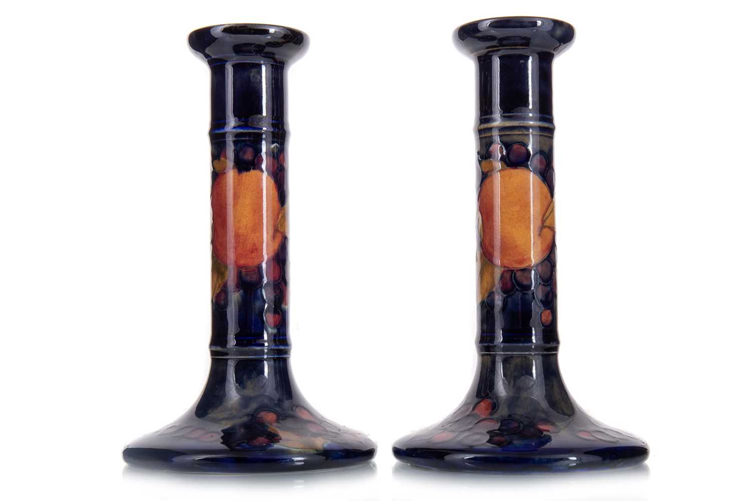 WILLIAM MOORCROFT (BRITISH, 1872-1945), PAIR OF 'POMEGRANATE' PATTERN CANDLESTICKS EARLY 20TH CENTUR