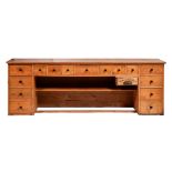 A pine counter, one side fitted with fifteen drawers and a till, 85cm h; 56 x 251cm The collection