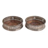 A pair of George III neo classical pierced and bright cut silver wine coasters, with beaded rim