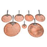 Seven graduated Victorian copper pan lids, with iron handle, two initialled CH or WCH, one by