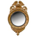 A Victorian giltwood convex mirror, the circular cavetto frame crested by an eagle on rock, shell
