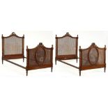 A pair of carved and parcel gilt walnut single bedsteads, c1920, with caned head and footboard,