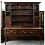 A George III oak dresser, the later boarded rack with twin spice cupboards and drawers, the lower