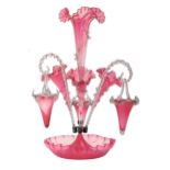 A Victorian cranberry glass flower stand, set with one larger and three smaller trumpet shaped vases