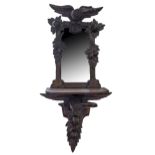 A Swiss 'Black Forest' carved and stained wood eagle shelf mirror, c1900, the rectangular plate