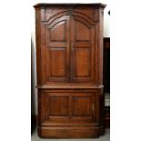 A George III architectural style oak standing corner cupboard, the break arched cornice with