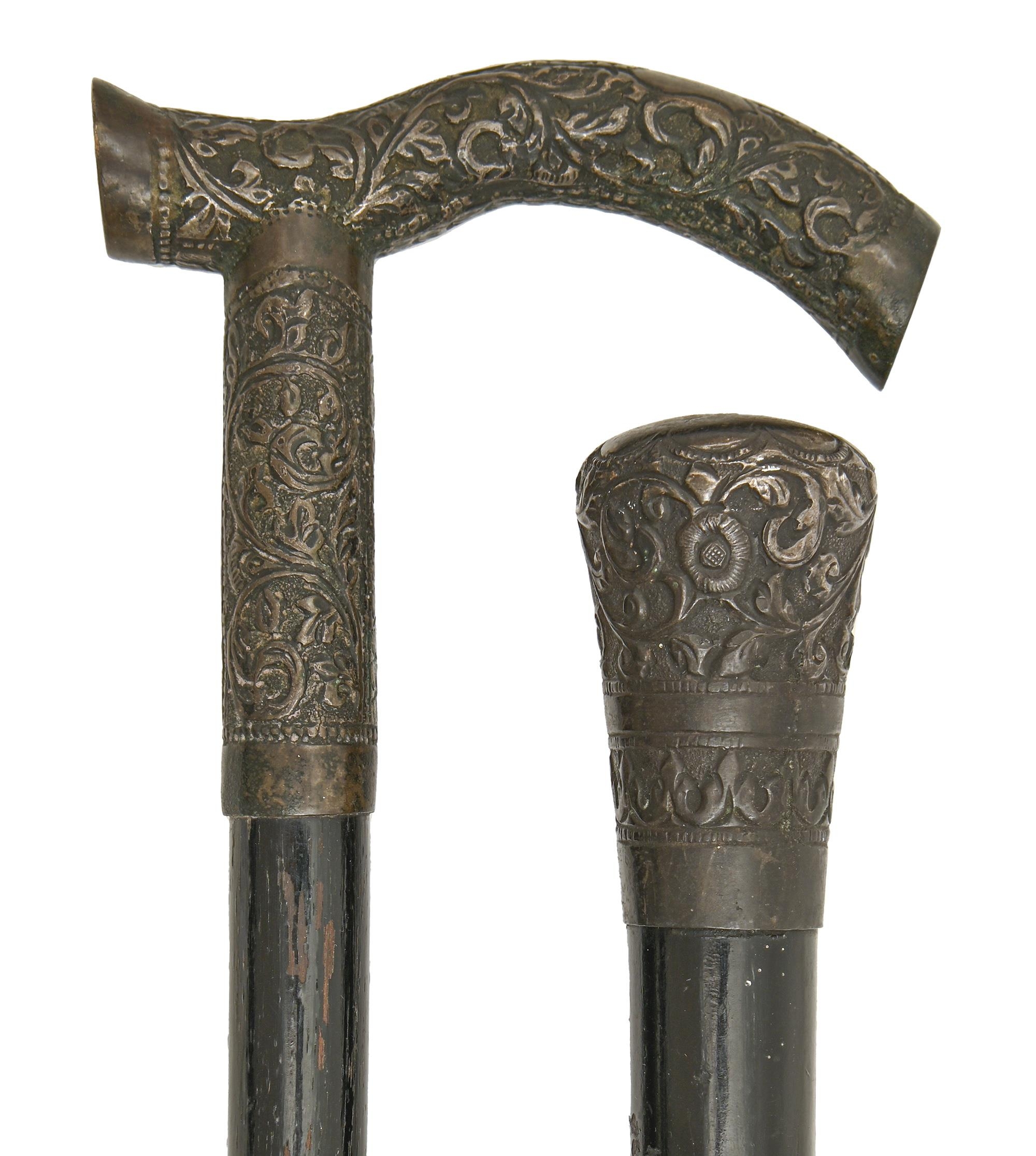 Two Indian silver repousse mounted ebonised canes, late 19th c, the pommel or tau handle typically