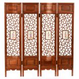 A Chinese hardwood four leaf screen, of open asymmetrical design with central inset famille rose