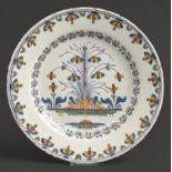 An English polychrome Delftware plate, Lambeth, c1770, painted with a stylised tree and fence,