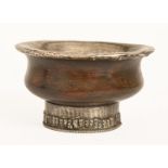 A Tibetan or Mongolian silver lined wood tea bowl, the foot with repousse silver collar, 10cm diam