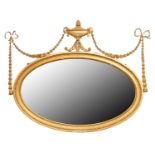 An Edwardian oval neo classical giltwood and composition mirror, surmounted by an urn and festoons