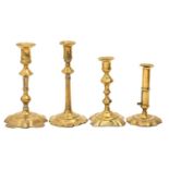 Four English brass candlesticks, mid 18th c,  including petal based and ejector examples, 22-26cm