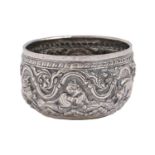 A Burmese silver repousse bowl, early 20th c, worked in high relief with elephant, tiger and other