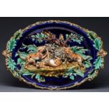 A Sarreguimines majolica plaque, pre 1881, modelled in high relief with three dogs fighting a