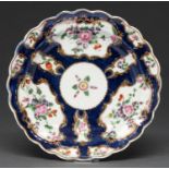A Worcester scale blue ground plate, c1770, painted with flowers and festoons in gilt reserves, 19cm