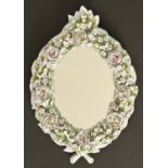A German porcelain floral encrusted mirror, c1900, ebonised wood back and strut, 34cm h Silvering of