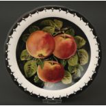 A Wemyss ware plate, c1900, painted by Karel Nekola with three apples on a black ground in scalloped