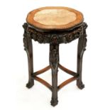 A Chinese carved hardwood stand, c1900, with pink stone inset top and pierced apron, on four legs