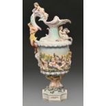A German porcelain ewer, c1900, moulded in high relief with infants and dolphins and supported by