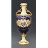 A Coalport vase, c1910, of shield shape, painted with a landscape in raised and gilt cartouche