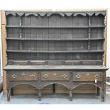 A George III oak dresser and rack, the base with boarded top, fitted with three drawers, on turned