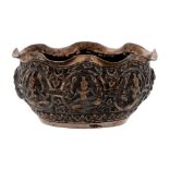 A Burmese silver repousse bowl, early 20th c, decorated with eight deities beneath wavy rim, 11cm
